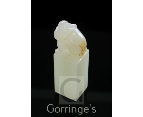 A Chinese small pale celadon jade seal, surmounted by the carved figure of a rabbit with a russet skin inclusion to its rear,