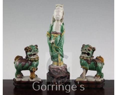 Three Chinese Sancai glazed biscuit figures, early 18th century, the first modelled as He Xiangu standing on a rockwork base,