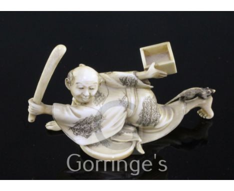 A Japanese ivory okimono of a ratcatcher, Meiji period, the figure crouching and holding a stick and a tray in each hand, the