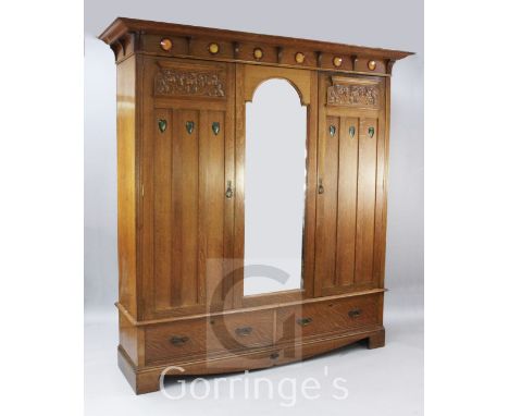 Shapland & Petter of Barnstaple. An Arts & Crafts oak triple wardrobe, the cornice inset with six Ruskin type pottery circula