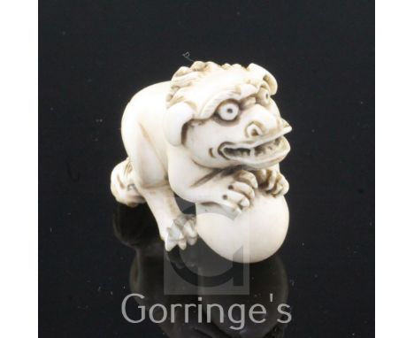 A Japanese ivory netsuke of a shi-shi, Edo period, standing on its haunches and grasping a ball, indistinctly signed, 4cm