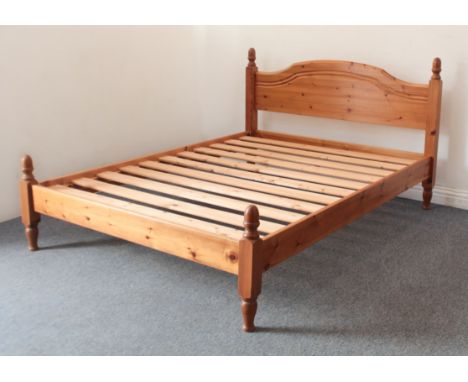 A pine double bed frame - with arched, panelled headboard, footboard and pine slatted bed base. (LWH 204 x 148 x 98cm)