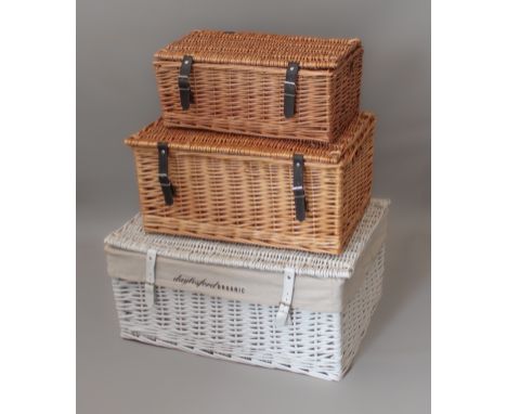 Three wicker hampers - a white Daylesford hamper (LWH 64 x 46 x 31cm) and two smaller (LWH 46 x 30 x 19cm).
