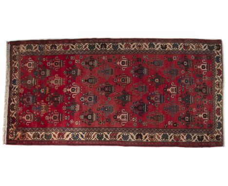 A Quashqai style hand-woven rug With a red ground and geometric decoration.274cm x 137cmQty: 1Generally good condition with s