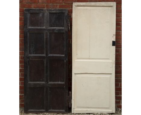 An oak eight-panelled door together with another One side painted black, the other side painted cream, with shaped H hinges; 