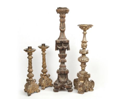 Four giltwood carved candlesticks To consist of a pair with twisting supports on carved triform bases; a single Neoclassicall