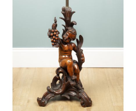 An Antique continental walnut table lamp The lamp in the form of a putti holding a fruiting vine branch aloft, on a scroll-fo