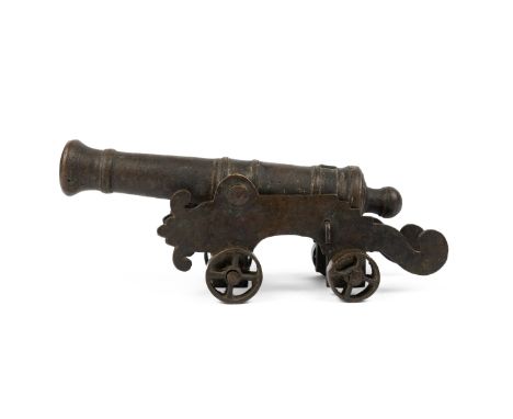 A small bronze model of a cannon With ring turned decoration, the gun carriage of shaped profile with spoked wheels.25cm long