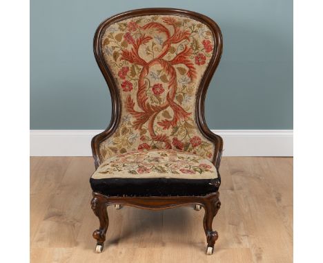 A 19th century mahogany-framed ballon-back nursing chair With needlework upholstery, floral rosettes to the hips of the cabri