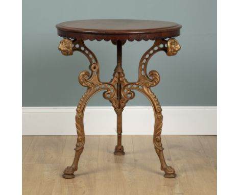 A cast iron gold-painted Coalbrookdale occasional table With a later mahogany top and a scalloped apron. The base with lion m