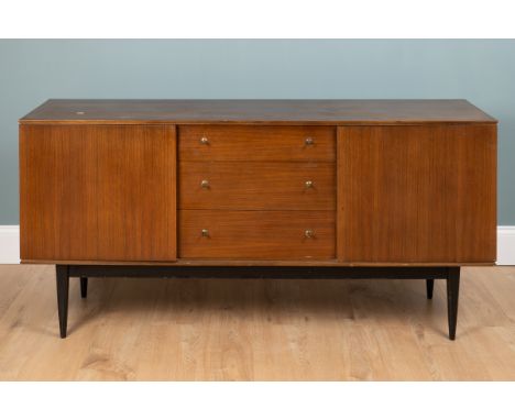 A mid-century teak sideboard With three drawers enclosed by two cupboards on an ebonised base with tapering square section le