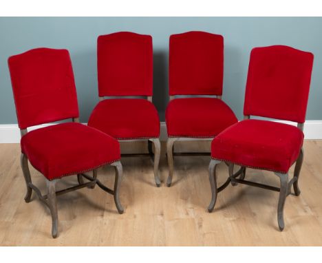 A set of four OKA dining chairs With red upholstery and overstuffed seats on limed oak cabriole legs united by shaped H-stret