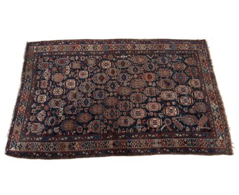 An early 20th-century woollen hand-woven Khamseh rug The blue ground with a repeating qum style motif intermingled with peaco