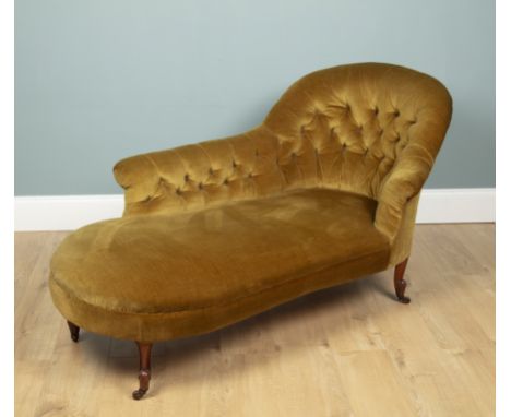 A Victorian green upholstered chaise long With a button upholstered back and standing on carved walnut legs terminating in ce