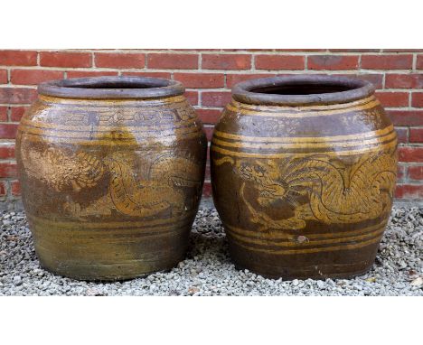 Two similar Chinese ovoid ceramic planters Each decorated with dragons, with differing borders just beneath the rim.The large