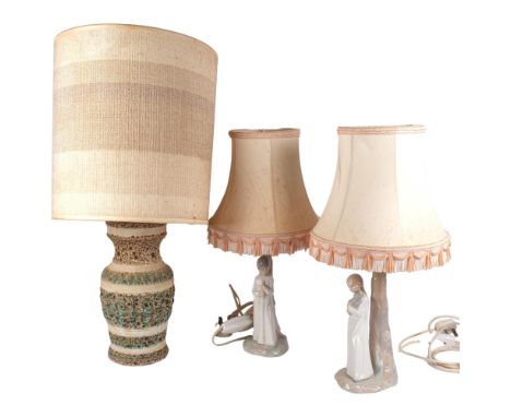 A pair of Spanish figure table lamps and shades, and an embossed pottery table lamp with shade 