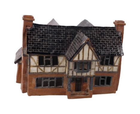 A handmade and glazed pottery lamp, in the form of a Tudor house, 31cm across 