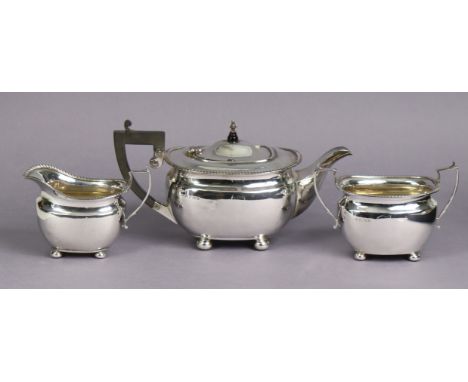 A George VI silver three-piece tea service in the regency style, of compressed oblong form with gadrooned rims, each on four 