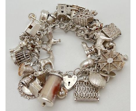 A vintage double curb chain silver charm bracelet with padlock clasp and safety chain. Complete with 41 silver and white meta
