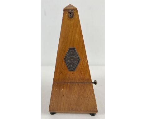 A vintage wooden cased Maelzel metronome raised on tripod wooden feet and with brass plaque to door. In working order. Approx