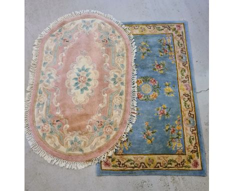2 vintage Chinese design rugs. A rectangular pale blue ground rug and an oval shaped pink ground rug with tasselled edges. Bo