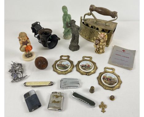 A box of assorted vintage misc items to include lighters, ceramic Hummel figurine, penknife, brass flat iron and carved items