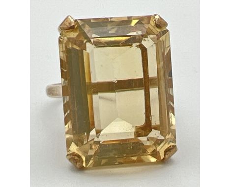 A 9ct gold cocktail ring set with a large emerald cut citrine stone. Pierced work scroll detail to mount. Stone approx. 20 x 