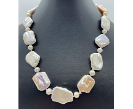 An 18" alternating large square shaped baroque pearl and round cultured pearl necklace. In white, peach and lilac tones, with