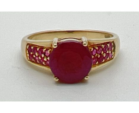 A modern design 9ct gold ruby set dress ring. Central round cut ruby with 8 small round cut rubies set to each shoulder. Full