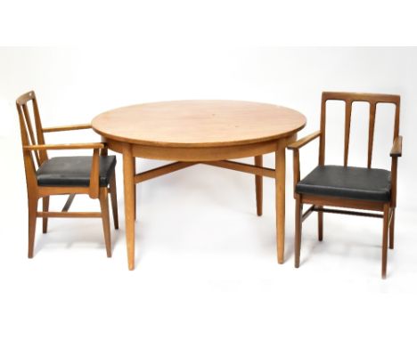 A retro teak dining suite comprising a circular extending table with single fold-out leaf, raised on turned tapering cross st