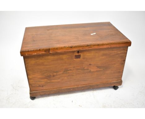 A 19th century stained wooden chest with iron drop handles, the lift-up top enclosing an interior with candle shelf, the whol