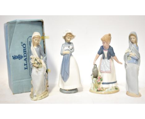 LLADRÓ; two porcelain figures comprising a seated lady with a bunch of lilies, boxed and a figure of a standing lady holding 