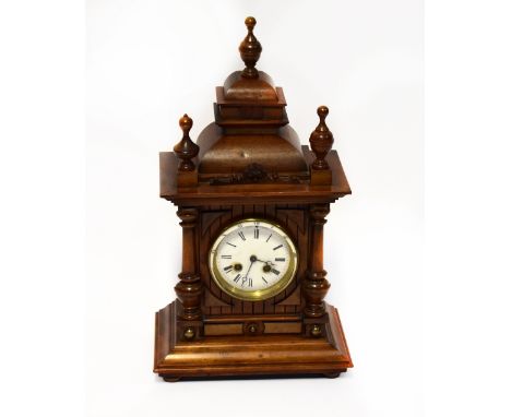 An early 20th century oak cased mantel clock of architectural form, with key wind chiming French movement, the white enamelle