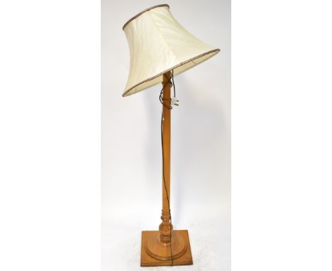 An oak standard lamp to spreading circular base and mounted on a square plinth, height 149cm, with associated shade. CONDITIO