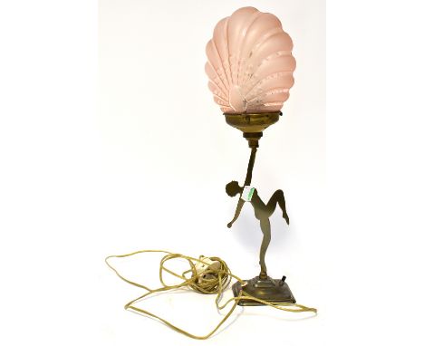 An Art Deco base metal figural table lamp, with a silhouette of a female dancer holding aloft a peach glass scalloped shade, 