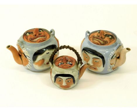 JAPANESE TEAPOTS Three Japanese teapots, each decorated in relief with Noh Theatre Masks. (Two lacking cane handles. The two 
