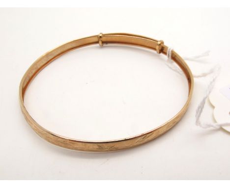 A Modern Expanding Bangle, with bright cut engraved decoration, stamped "375" (3grams). 