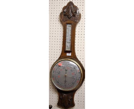 A mid 20th century relief carved oak aneroid two dial wheel barometer