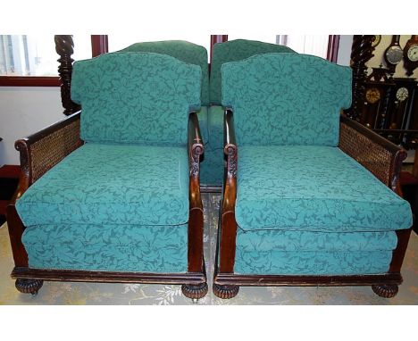 An early 20th century mahogany and cane inset three piece Bergere suite comprising; two seater sofa and pair of armchairs, ea