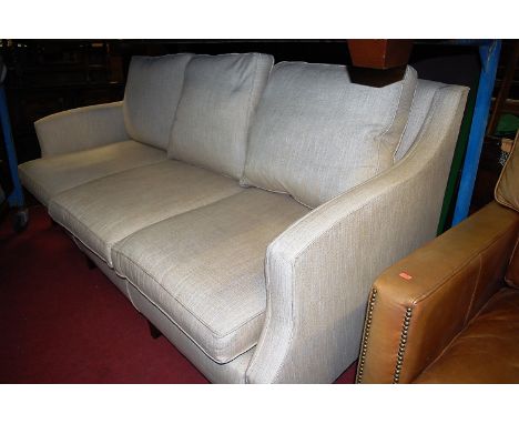A contemporary fabric upholstered three-seater sofa, raised on slightly outswept supports, w.205cm