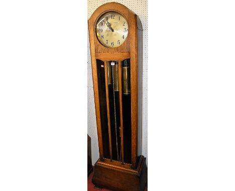 An Art Deco oak long case clock, having a silvered circular dial with three train movement, glazed trunk door, with pendulum 