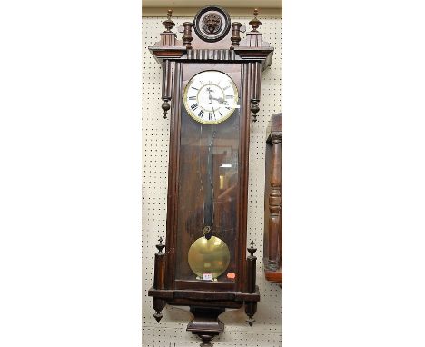A circa 1900 Vienna walnut cased drop trunk wall clock, having a white enamel circular dial with pendulum (lacking weights)