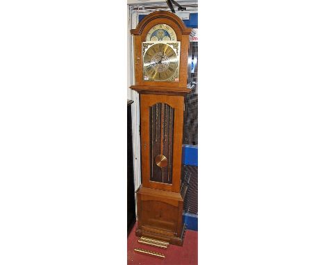A contemporary oak long case clock, having a moon phase arched brass dial, three train movement, with pendulum and three weig