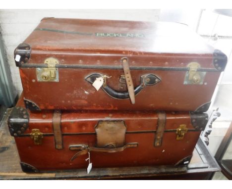 A LARGE VINTAGE BROWN TRAVELLING TRUNK with leather straps and brass fittings and another smaller  and a similar suitcase (3)