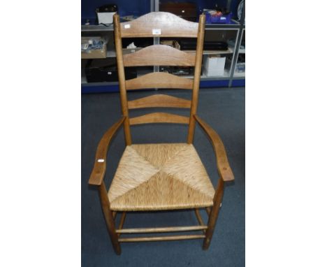 AN ARTS AND CRAFTS COTSWOLDS STYLE LADDER-BACK ARMCHAIR with a rush seat