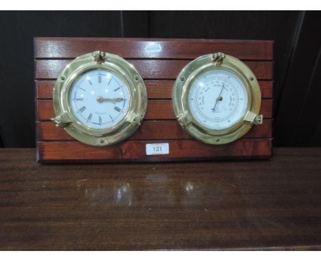A wall clock and barometer in the form of portholes mounted on wood