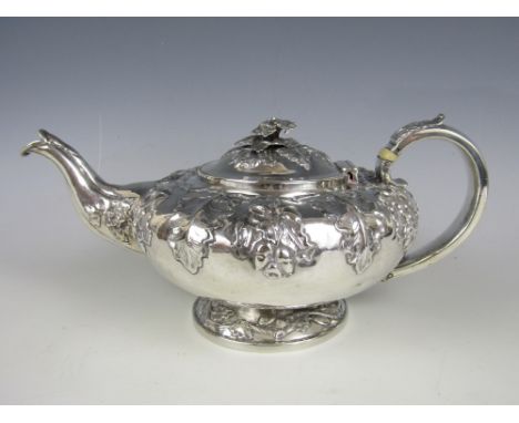 A William IV silver tea pot, of compressed oblate form raised over a spreading foot, repousse moulded and chased with a folia