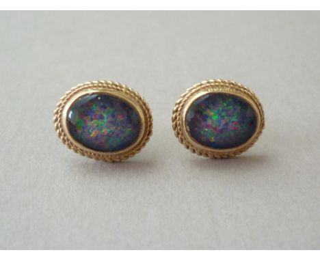 A pair of black opal stud earrings, each cabochon stone of approximately 1.10ct, bezel and rope twist set 