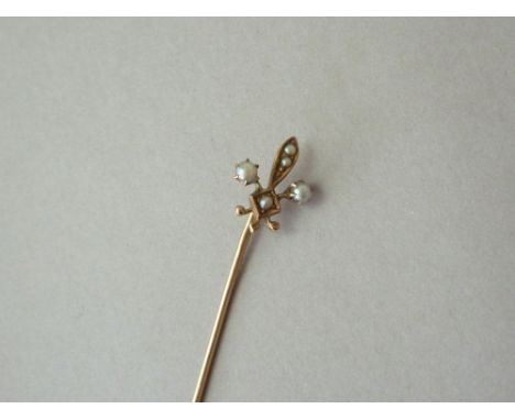 An early 20th Century seed pearl stick pin, the terminal modelled in the form of a fleur-de-lis, on 10k gold 