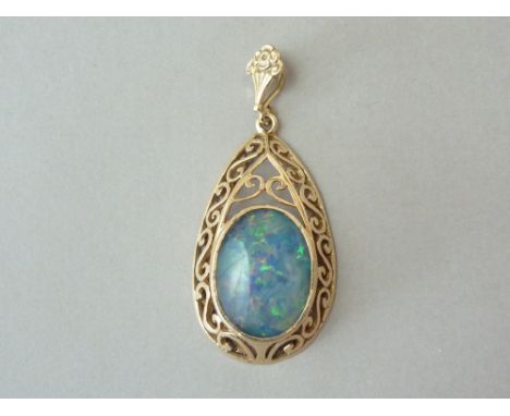 A black opal pendant, the oval cabochon stone of approximately 6ct, bezel set above a scrolling 9ct gold openwork teardrop mo